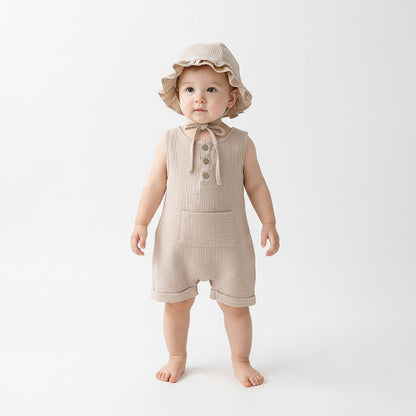 Petite fille debout portant une combishort bébé mousseline beige lin naturel avec chapeau bob à volants et cordelette – Choupinoo