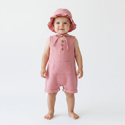 Petite fille debout portant une combishort bébé mousseline rose saumon avec chapeau bob à volants et cordelette – Choupinoo