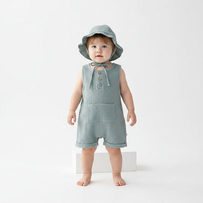 Petite fille debout portant une combishort bébé mousseline vert sauge avec chapeau bob à volants et cordelette – Choupinoo