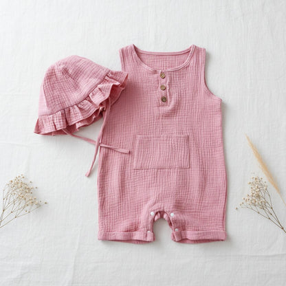 Combishort bébé été en mousseline rose saumon avec chapeau bob à volants, flat lay minimaliste vue de dessus sur fond lin blanc – Choupinoo