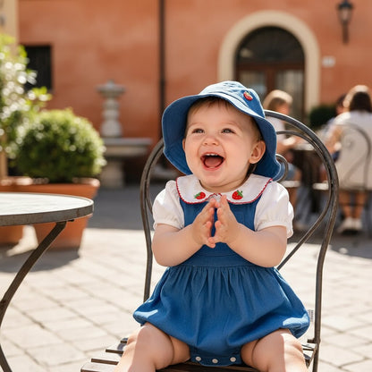 Bebe fille souriante en ensemble coton bleu motif fraise assise sur terrasse italienne plan serre - Choupinoo