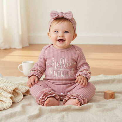 Bébé fille souriante en barboteuse waffle knit rose assise sur lin naturel – tenue chaude et douce pour sortie maternité et crèche | Choupinoo