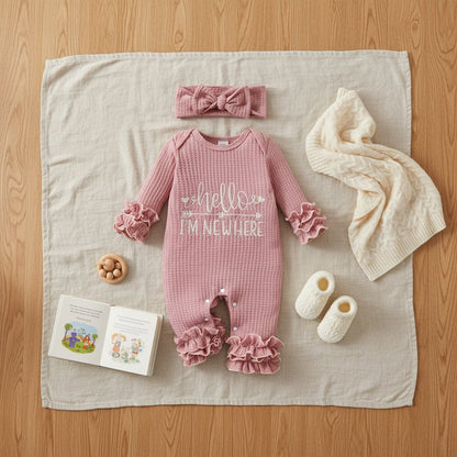 Barboteuse bébé fille waffle knit rose et bandeau nœud en flat lay sur lin naturel avec objets lifestyle – cadeau naissance fille idéal