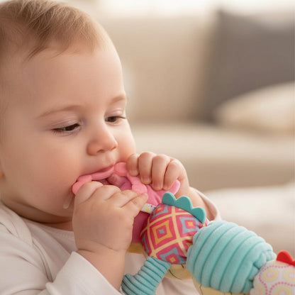 petite main qui serre l'anneau rose du doudou peluche caméléon rose contre les gencives, soulagement visible, légère bave