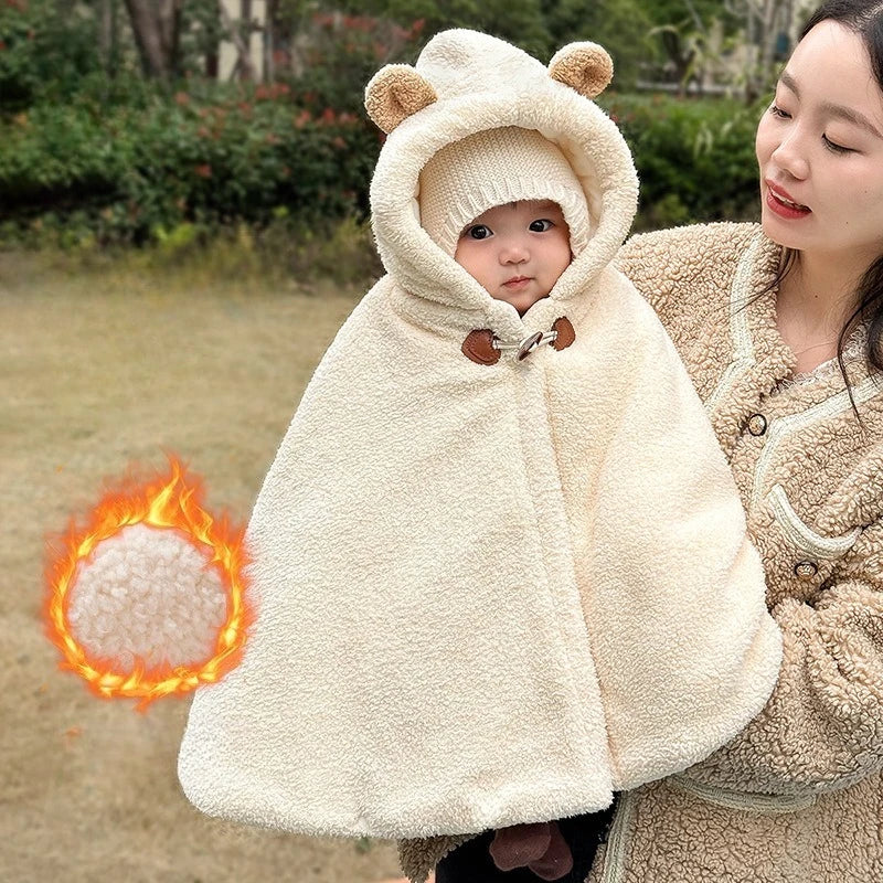 Bébé dans les bras d’un adulte, portant une cape d’hiver écrue à capuche avec oreilles d’ours - Choupinoo