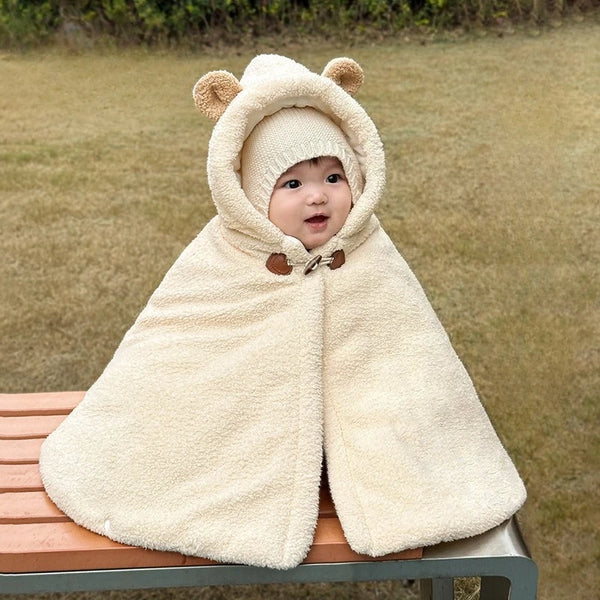 Bébé assis sur un banc avec une cape écrue à capuche ornée d’oreilles d’ours et une fermeture au col - Choupinoo