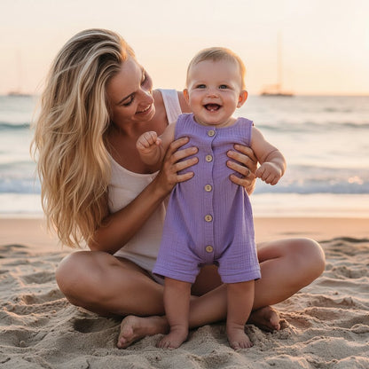Bebe souriant en combinaison ete coton lavande tenu par sa maman sur la plage au coucher du soleil - Choupinoo
